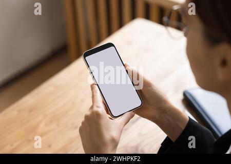 Schermo vuoto dello smartphone nelle mani di una giovane donna d'affari Foto Stock