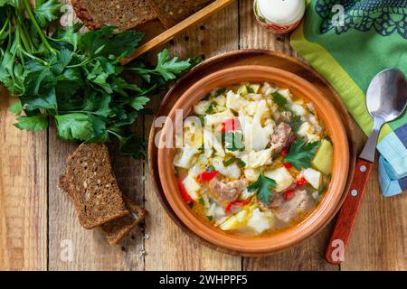 Zuppa tradizionale ungherese spessa con manzo, verdure e gnocchi su un tavolo di legno. Cena calda o pranzo. Disposizione piatta, vista dall'alto. Foto Stock