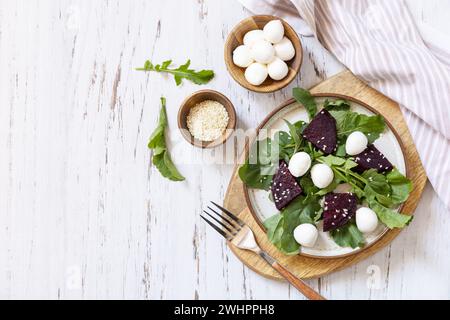 Sana insalata dietetica con rucola, spinaci, barbabietole, mozzarella e condimento con vinaigrette su un tavolo di legno. Calorie basse che muoiono Foto Stock
