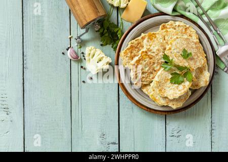 Cotolette vegetariane fritte o frittelle. Frittelle di verdure al cavolfiore con formaggio su un tavolo da cucina rustico. Vista dall'alto. Poliziotto Foto Stock