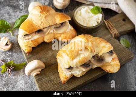 Croissant con formaggio cremoso e funghi su fondo in pietra. Pasticceria francese, gustosi panini appena sfornati. Cucina vegana. Foto Stock