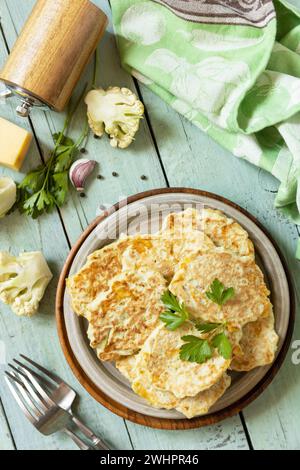 Frittelle di cavolfiore con formaggio su un tavolo da cucina rustico. Cotolette vegetariane fritte o pancake. Vista dall'alto. Foto Stock