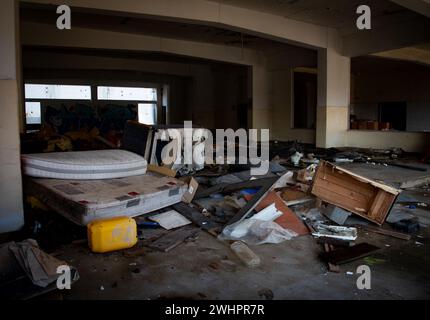 Interno di una vecchia casa abbandonata con mobili danneggiati e pavimento disordinato Foto Stock