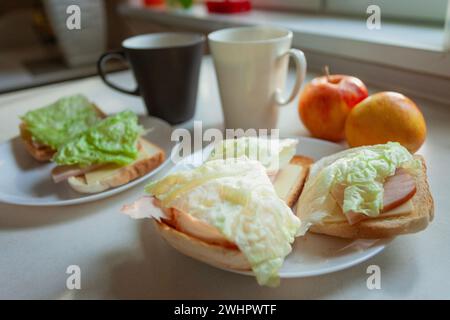 Sandwich con pane tostato, affettati e insalata per colazione con due mele Foto Stock