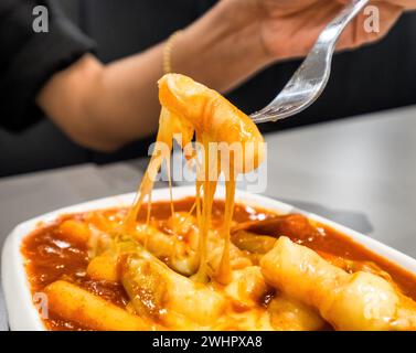 Le donne alla forcella di supporto con tteokbokki formaggio tratto Foto Stock