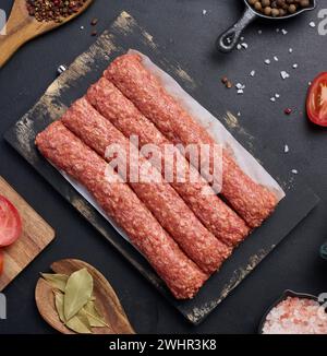 Salsicce crude al kebab di lula su tavola e spezie, vista dall'alto Foto Stock