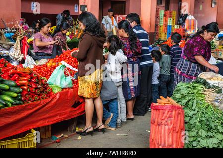 Chichicastenango, Guatemala. Famiglia acquistare ortaggi freschi nel mercato coperto. Foto Stock