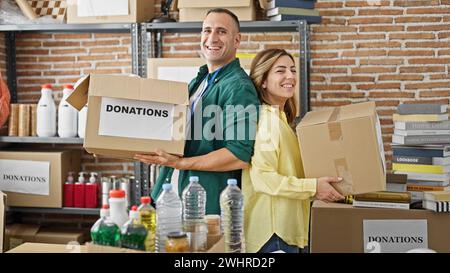 Uomini e donne volontari che tengono pacchetti di donazioni sorridenti al centro di beneficenza Foto Stock