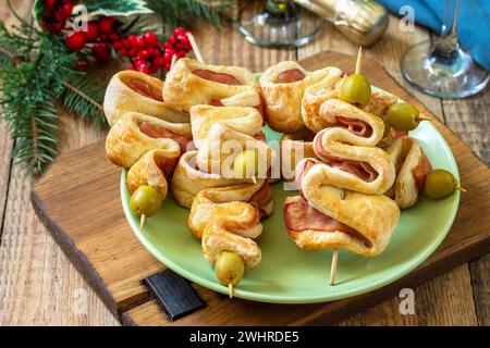 Cibo di Natale e Capodanno. Pasta sfoglia natalizia con olive e pancetta su un tavolo di legno. Foto Stock