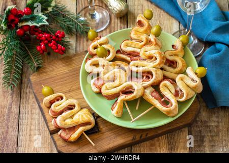 Cibo di Natale e Capodanno. Pasta sfoglia natalizia con olive e pancetta su un tavolo di legno. Foto Stock