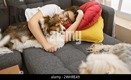 Donna ispanica che dorme sul divano con il cane da pastore delle shetland in un accogliente soggiorno Foto Stock