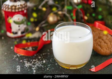 Concetto di vacanza. Latte e biscotti fatti in casa per Santa Clause vicino all'albero di Natale. Foto Stock