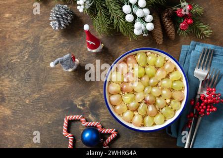 Insalata natalizia invernale. Deliziosa insalata con pollo, formaggio, noci e uva su un tavolo festivo. Vista dall'alto. Copia spazio Foto Stock