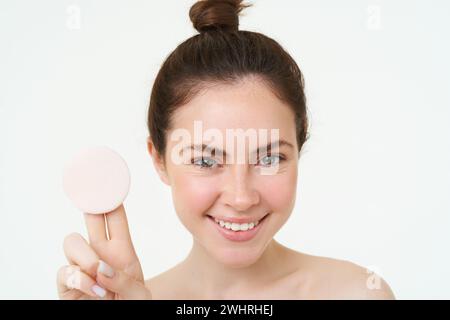 Cura della pelle e benessere. La giovane donna mostra un panno di cotone cosmetico, si toglie il trucco, usando il detergente per il viso, lavandosi il viso con l'ingegno Foto Stock