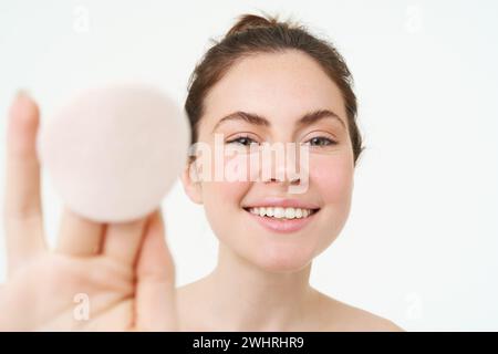 Cura della pelle e benessere. La giovane donna mostra un panno di cotone cosmetico, si toglie il trucco, usando il detergente per il viso, lavandosi il viso con l'ingegno Foto Stock