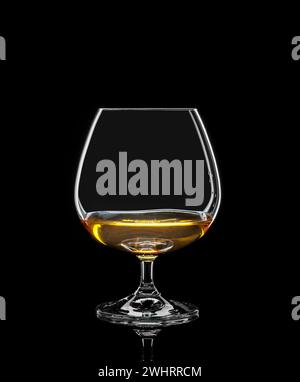 Bicchiere cognac con bevanda su nero Foto Stock