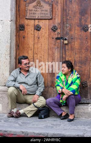 Antigua, Guatemala. Coppia di mezza età che riposa, parlando. Plaza de Armas, Semana Santa. Foto Stock