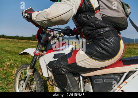 Un motociclista dotato di equipaggiamento professionale, guida il motocross su prati pericolosi, allenandosi per una gara imminente. Foto Stock