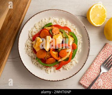 Pollo cotto in un wok con peperoni colorati e riso. Foto Stock