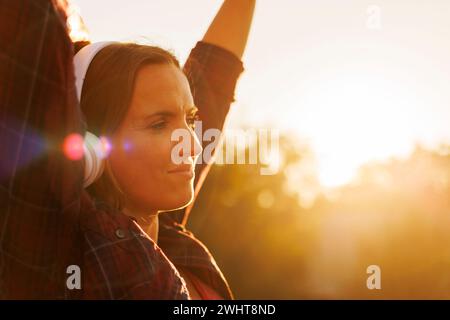 Donna che ama il tramonto con le cuffie Foto Stock