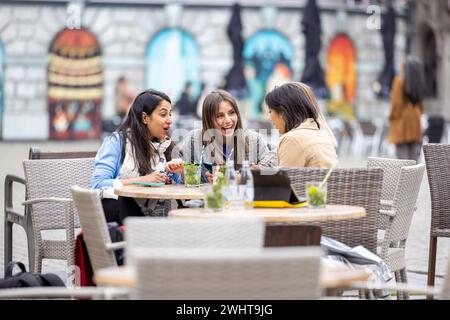 Diverse donne d'affari che gustano cocktail e condividono sorprese nella città europea Foto Stock