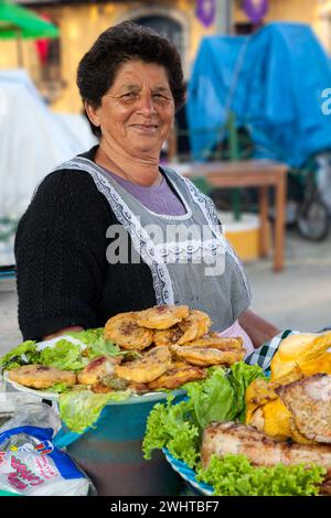 Antigua, Guatemala. Donna di mezza età che vende spuntini di fronte ad una Chiesa durante Semana Santa. Foto Stock