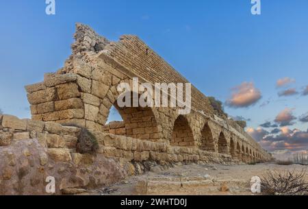 Vecchio acquedotto costruito dai Romani contro il cielo al tramonto a Cesarea Israele Foto Stock