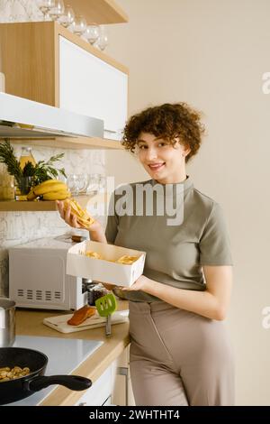 Una donna sorridente toglie la pappardelle dalla scatola di cartone Foto Stock