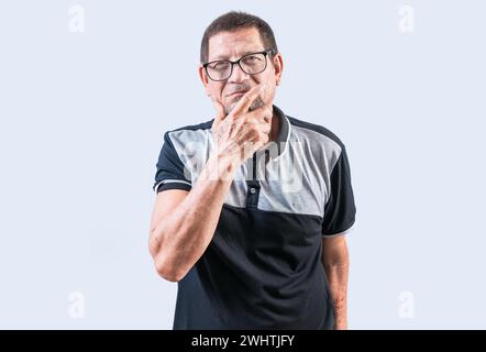 Pensivo anziano con la mano sul mento che meditava isolato. Persone anziane che pensano con la mano sul mento guardando la telecamera Foto Stock