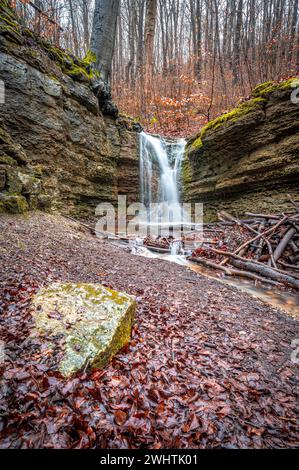 La cascata nella foresta di Rautal a Burschenplatz in inverno, Jena, Turingia, Germania Foto Stock