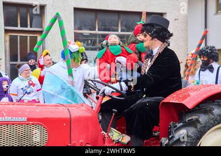 Sfilata di carnevale di Gaudiwurm con un bambino addormentato su un trattore l'11 febbraio 2024 a Marktoberdorf, Germania. Foto Stock