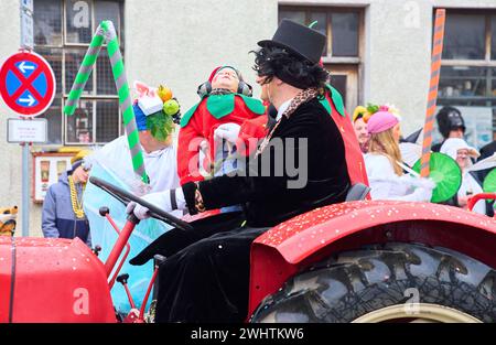 Sfilata di carnevale di Gaudiwurm con un bambino addormentato su un trattore l'11 febbraio 2024 a Marktoberdorf, Germania. Foto Stock