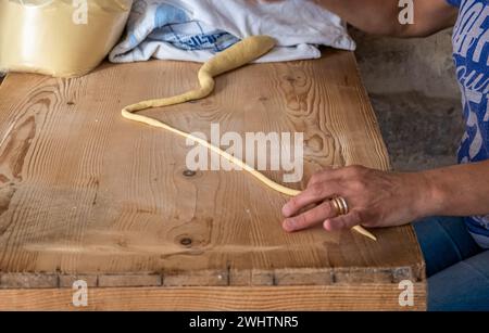 Primo piano sulle mani di una donna che prepara le orecchiette, la tipica pasta pugliese, per strada nel centro storico di Bari, Puglia, Italia Foto Stock