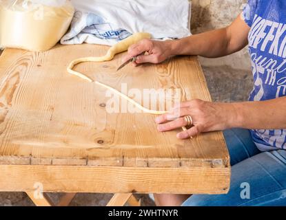 Primo piano sulle mani di una donna che prepara le orecchiette, la tipica pasta pugliese, per strada nel centro storico di Bari, Puglia, Italia Foto Stock
