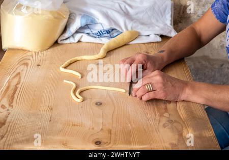 Primo piano sulle mani di una donna che prepara le orecchiette, la tipica pasta pugliese, per strada nel centro storico di Bari, Puglia, Italia Foto Stock