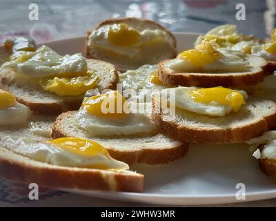 Mini uova fatte in casa con il lato soleggiato sul pane tostato: Una deliziosa presentazione per la colazione Foto Stock