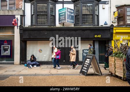 Un senzatetto siede fuori dal negozio chiuso, Oxford High Street Foto Stock