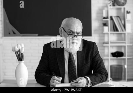 Professore tenendo un libro e indicando con un bastone di legno isolato su sfondo bianco. Conoscenza e concetto di istruzione tradizionale. Foto Stock