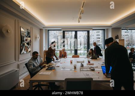 Un ambiente d'ufficio dinamico con un team multietnico che partecipa attivamente a una riunione d'affari in uno spazio di lavoro luminoso e moderno. Foto Stock