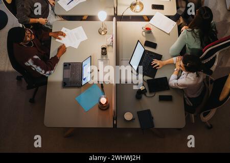 Vista dall'alto dei colleghi aziendali multigenerazionali che collaborano in una sala riunioni, evidenziando il lavoro di squadra, la strategia e la diversità. Foto Stock