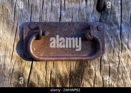 Vecchia maniglia della porta ruvida sulla vecchia porta di legno in verticale Foto Stock