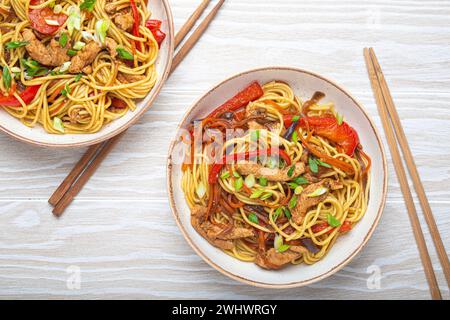 Due ciotole con Chow Mein o lo Mein, tradizionali spaghetti cinesi con carne e verdure, serviti con bacchette Foto Stock