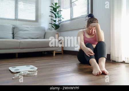 Donna obesa con agitazione grassa annoiata di dieta perdita di peso failÂ dieta grassa e scala donna asiatica triste su scala di peso a peso domestico Foto Stock