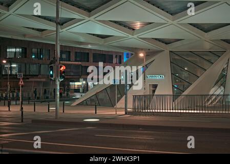 Bruxelles, Belgio 5-02-2024. Strade notturne del Belgio. Facciata dell'edificio Starbucks. Marciapiede illuminato. Sagome di persone per strada Foto Stock