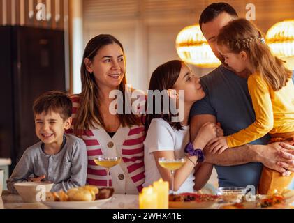 La grande famiglia felice sta pranzando nella sala da pranzo. Genitori e bambini si divertono a casa. Foto Stock