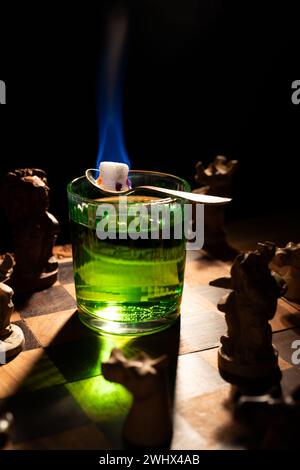 Preparare l'assenzio verde con zucchero e fuoco su una scacchiera Foto Stock