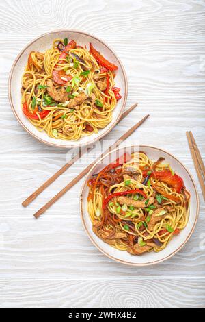 Due ciotole con Chow Mein o lo Mein, tradizionali spaghetti cinesi con carne e verdure, serviti con bacchette Foto Stock