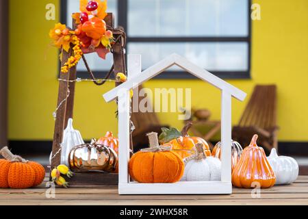 Decorazioni autunnali su portico di casa gialla all'esterno di zucca, lanterna, ghirlande e figura di casa e chiave. Festa di Halloween, autunno Foto Stock