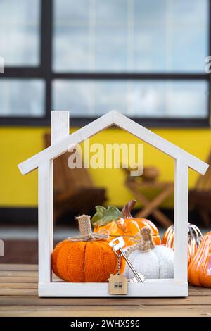 Decorazioni autunnali su portico di casa gialla all'esterno di zucca, lanterna, ghirlande e figura di casa e chiave. Festa di Halloween, autunno Foto Stock