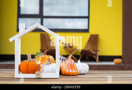 Decorazioni autunnali su portico di casa gialla all'esterno di zucca, lanterna, ghirlande e figura di casa e chiave. Festa di Halloween, autunno Foto Stock